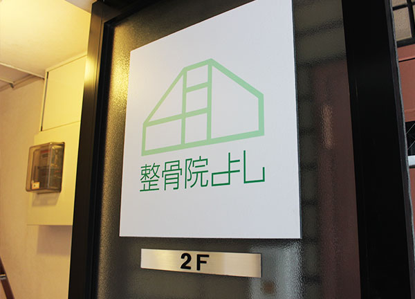 整骨院よし(階段を上がる前にあるドアには店舗の看板があります)